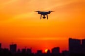 Drone flying over city at sunset